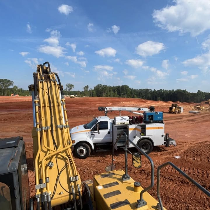 Our service truck with crane parked on a red clay job site next to an excavator